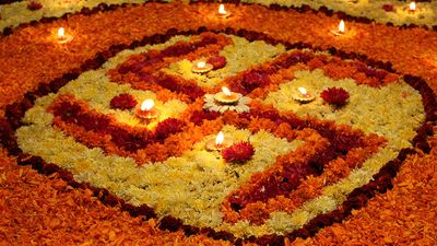 A background with a view of earthen lamps arranged on the holy Swastika design made of flowers, during Diwali festival in India.