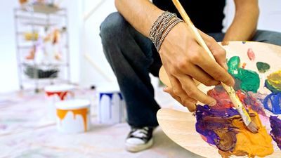Close-up of a palette held by a man. Mixing paint, painting, color mixing.