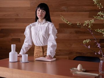 Japanese tidying expert Marie Kondo standing behind a wooden table. (KonMari Method)