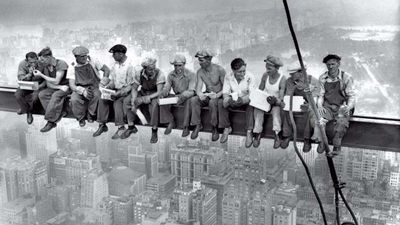 Lunch atop a Skyscraper. Eleven New York construction workers eat their lunches on a steel crossbeam atop the 70-story RCA building in Rockefeller Center, New York, New York, September 20, 1932. A staged photograph, the photographer is unknown, but it is sometimes attributed to Charles C. Ebbets. Ironworkers
